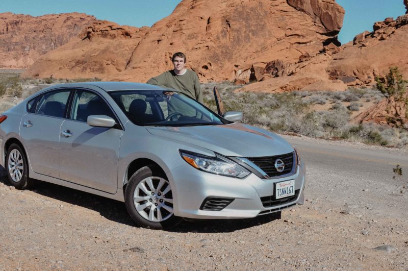 Posing with our rental car during a rental car road trip to Valley of Fire State Park in Nevada