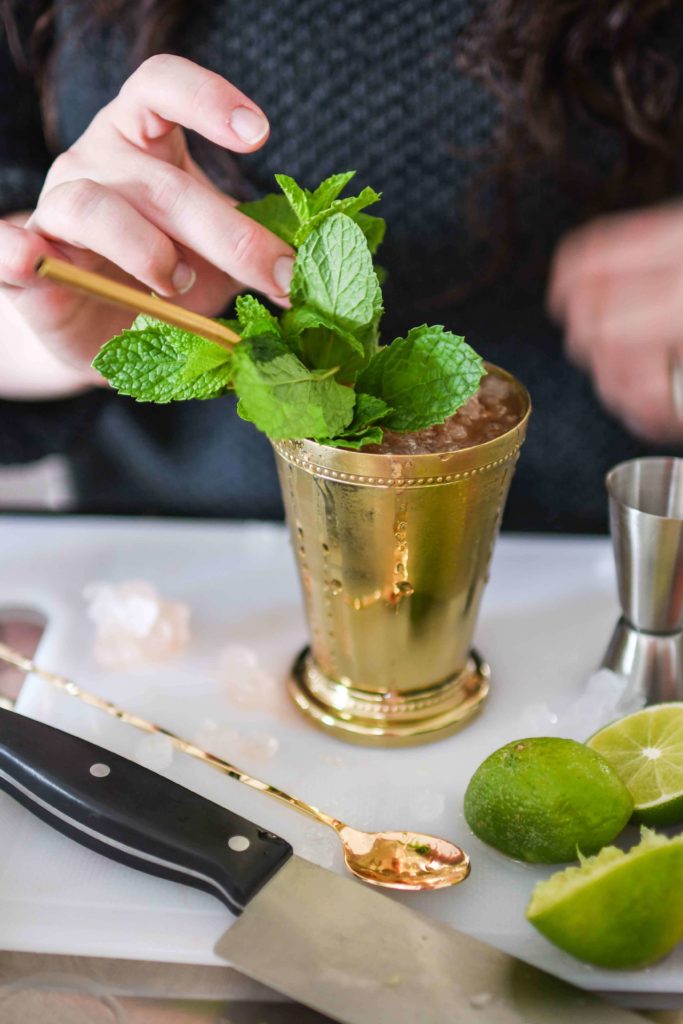 Adding large mint sprigs to the cocktail