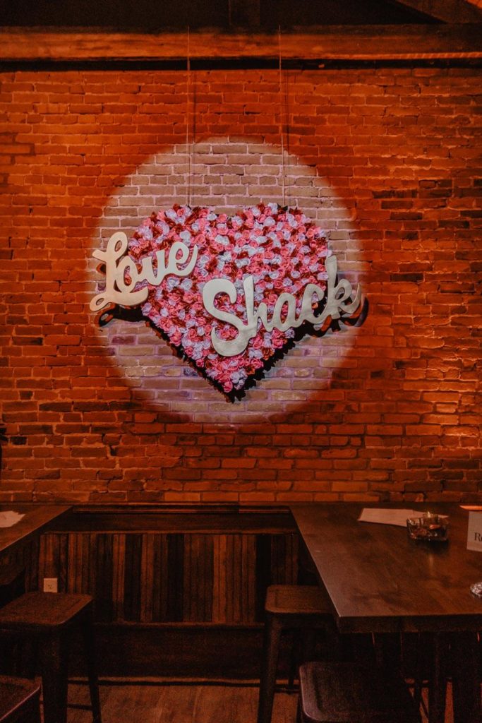 A large heart made up of paper roses in red, pink, and white.  "Love Shack" is scrolled across the heart in a cursive font. 