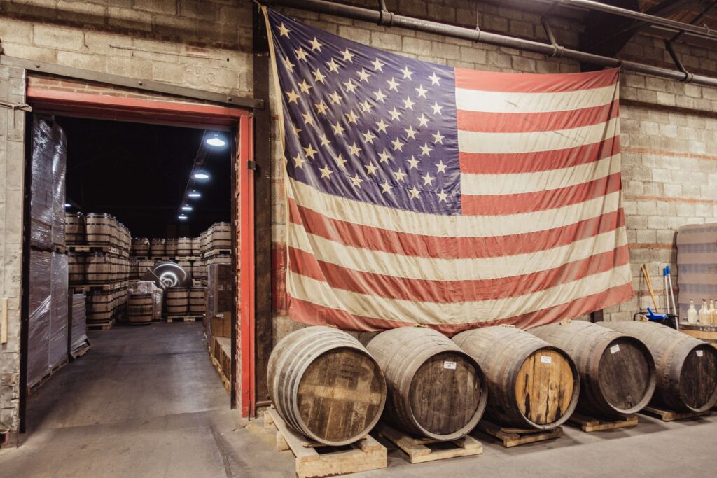 A large American flag over whiskey barrels at the Nelson Green Briar Distillery in Nashville - Nashville Weekend Itinerary