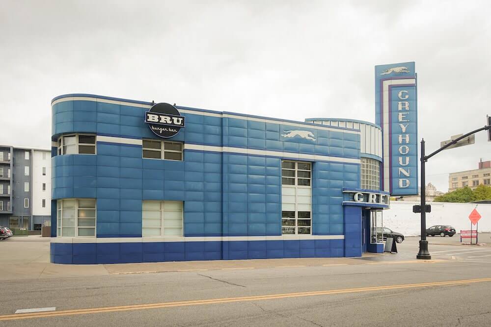 A dark blue, rounded building, made up of a series of tiles.  Each tile is made of metal, although it gives the illusion that it is filled with air and could be deflated with a poke.  The sign on the front reads "Greyhound" but on the side of the building it says "Bru Burger Bar"