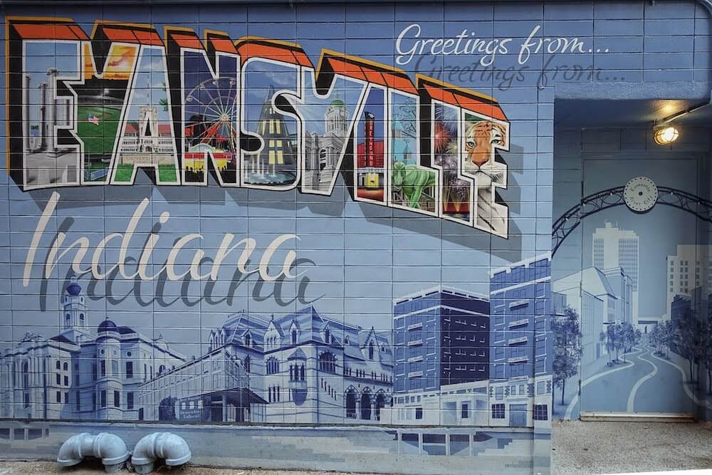 A colorful mural that reads "greetings From Evansville, Indiana." Each letter in Evansville shows a different landmark from the city. 