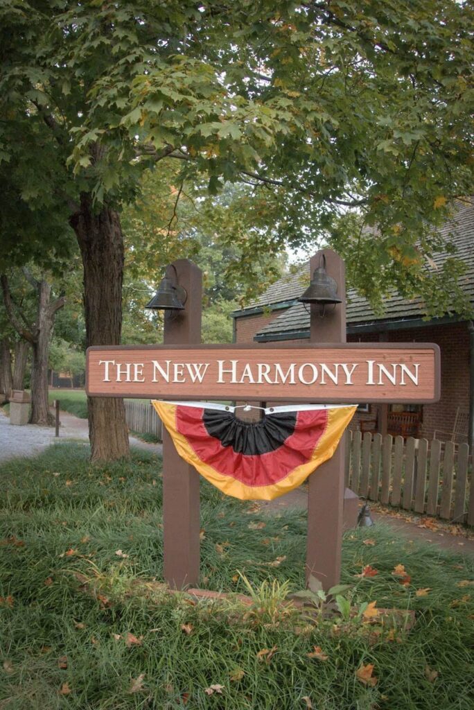 Sign that reads "New Harmony Inn" with a bunted German flag under it.  Two copper lights illuminate the sign. 
