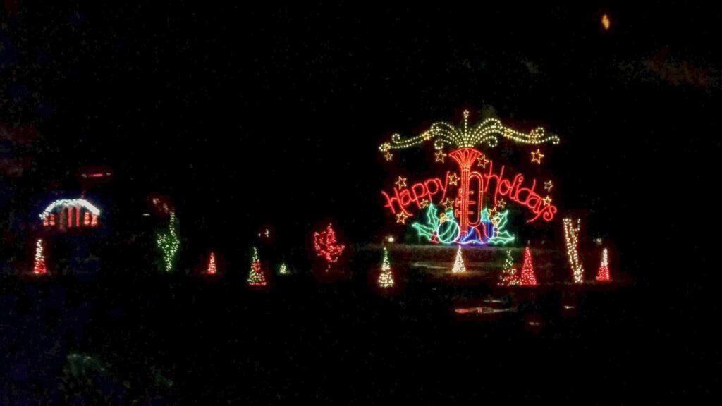 A Large Light display that reads "Happy Holidays"  With a large trumpet made out of lights shooting out swirls of light to symbolize music. 